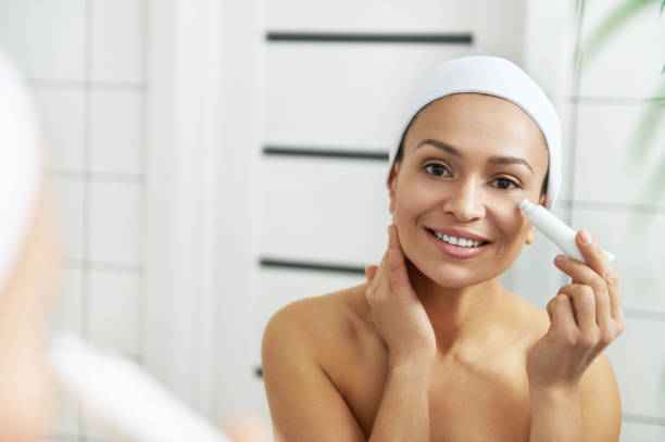 istock Woman applying cream under the eyes while looking at herself through the mirror 1290060714