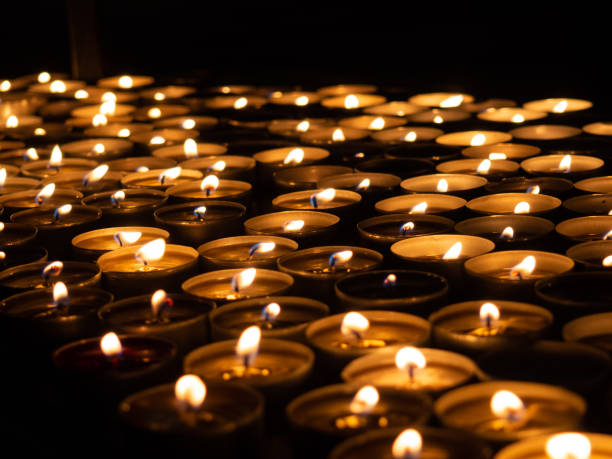 istock Tea candles burning on black background 1290062595