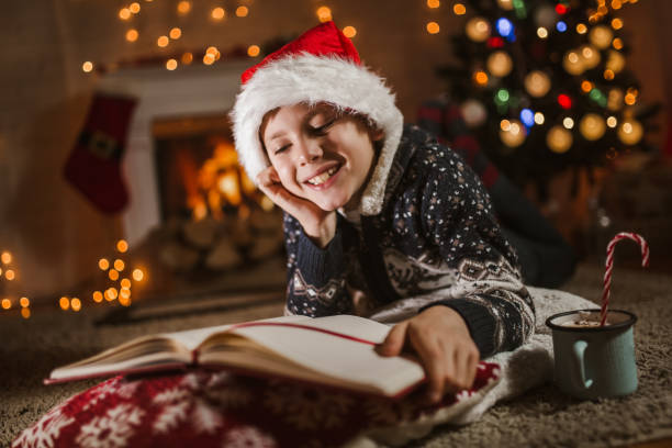 istock Boy, reading a book in front of a Christmas tree. 1290063808