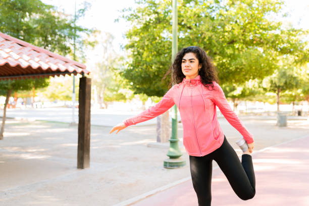 istock Hispanic woman doing leg stretches in the park 1290065036