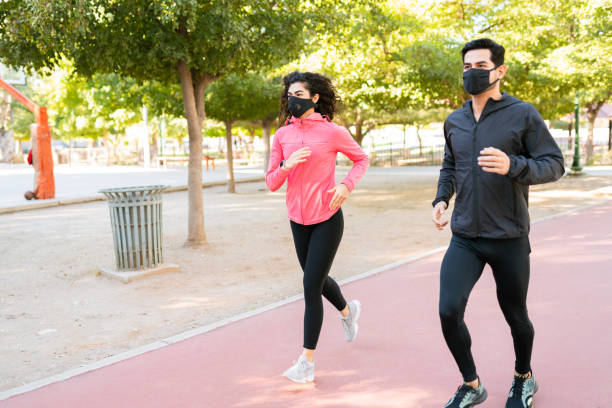 istock Good-looking pair with pface masks jogging in the running track 1290065063