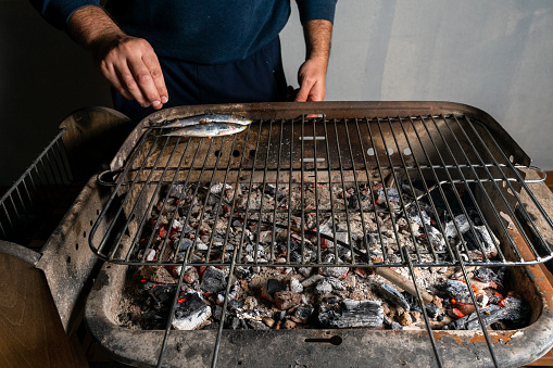 Man cooking a barbecue of fresh sardines on a charcoal barbecue. Healthy food concept