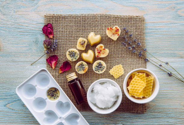 faire la mini cire fond pour diffuseur de lampe d’arôme au concept à la maison. outils ingrédients sur la cire d’abeille non blanchie de table, huile de coco solide, huile essentielle, fleurs séchées et moule en plastique. vue plate de pose. - coconut oil lamps photos et images de collection