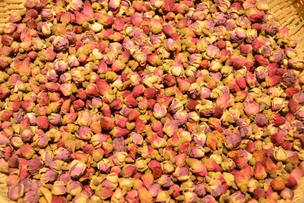 dried rose buds in the basket under bright light for sale in the market