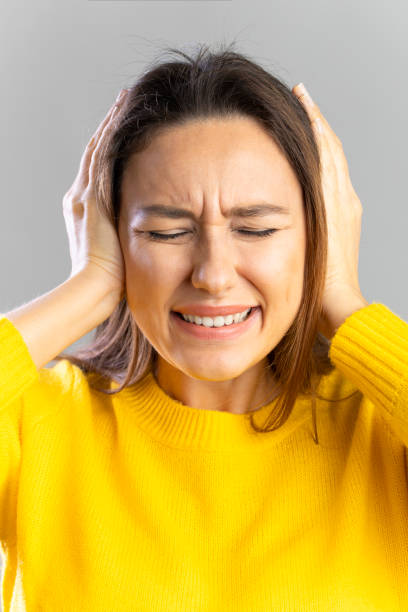 I don't want to hear it Portrait of angry young woman clenching teeth with hands covering ears hands covering ears stock pictures, royalty-free photos & images