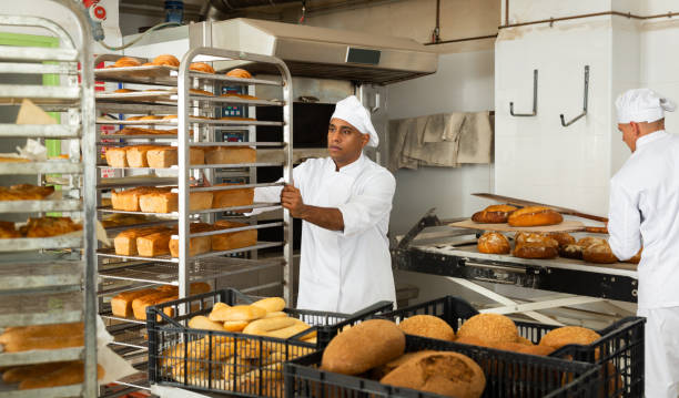 istock Confident baker carrying rack trolley with bread 1290067798