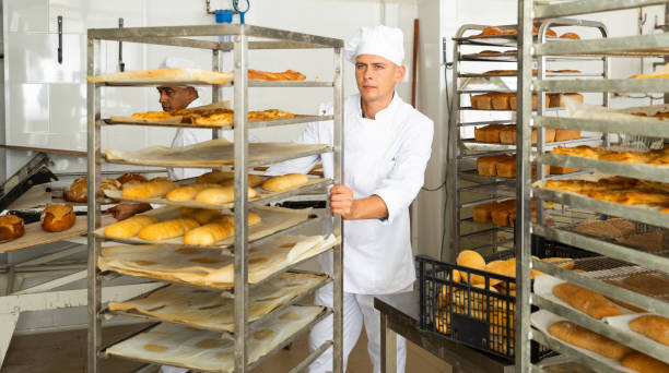 istock man in chefs uniform rolling trolley with bread in bakery 1290067812