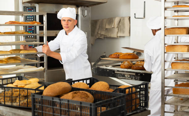 istock Man baker moves cart with prepared pastries 1290067821