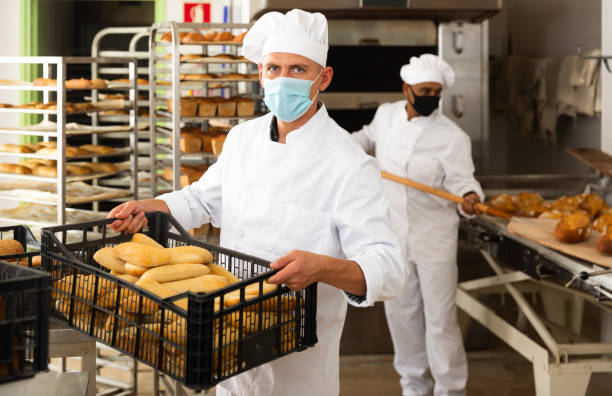 istock man in chefs uniform with bread in tray in bakery during virus 1290067841