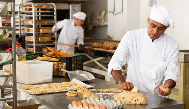 istock Male baker working with dough forming baguettes 1290069025