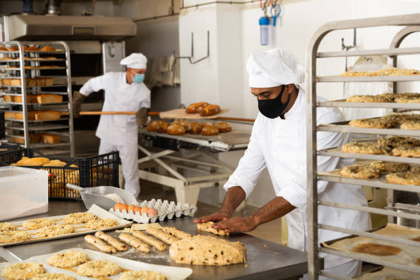 istock Male baker working with dough forming baguettes 1290069028