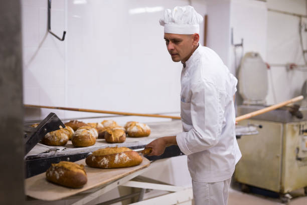 istock Baker takes out hot bread from oven 1290069055