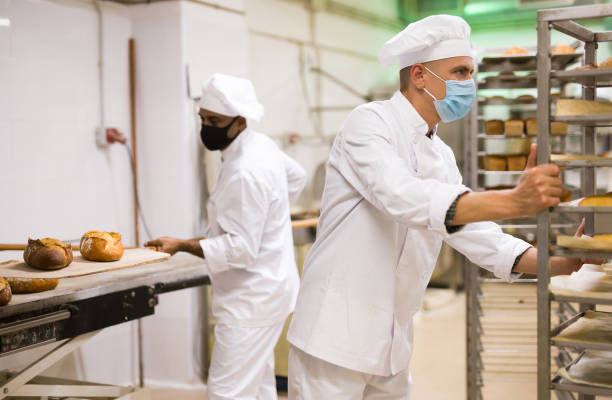Male baker carrying rack trolley with bread
