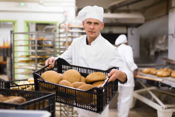 istock man in chefs uniform with bread in tray in bakery 1290069077