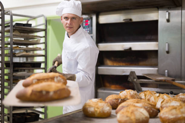 istock male baker with bread on baking shovel in kitchen 1290069093