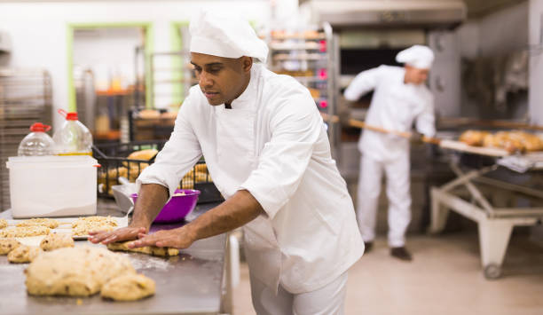 istock man in chefs uniform kneading dough in bakery 1290069098