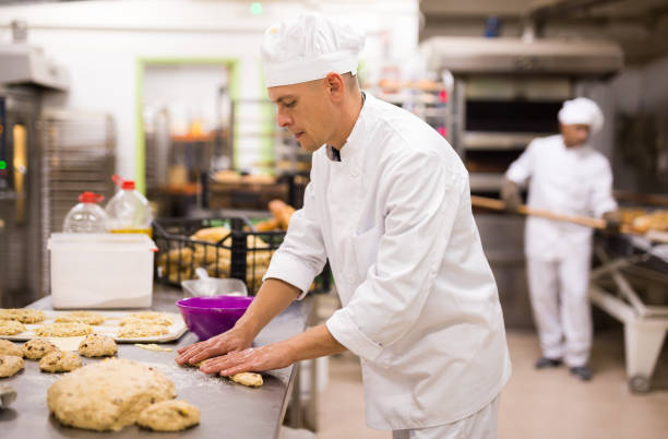 istock Male baker working with dough forming baguettes 1290069102