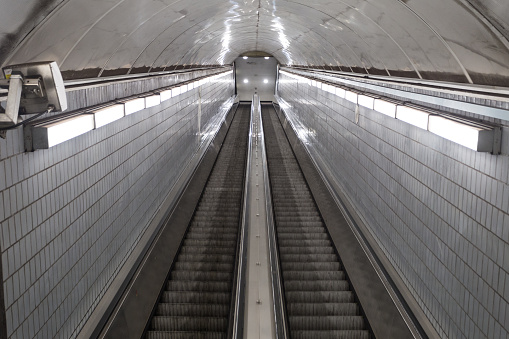 Bright lights leading down super long escalator leading to underground subway station