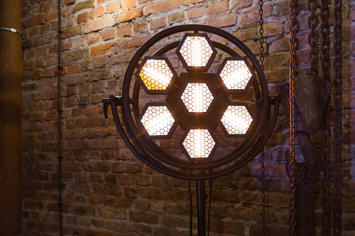 Modern stage light in hexagon shape against brick wall. Close up.