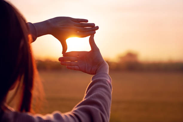istock Future planning concept, Close up of woman hands making frame gesture with sunset. 1290074282