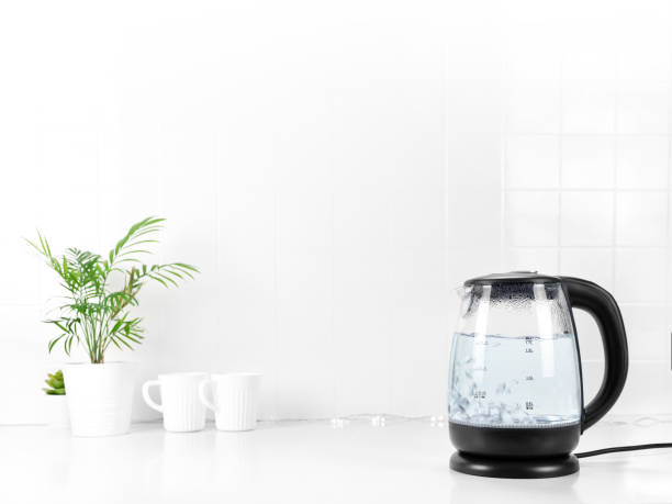 Glass transparent kettle on white kitchen table Glass transparent kettle on white kitchen table. Closeup. Nobody glass cup of boiling water stock pictures, royalty-free photos & images