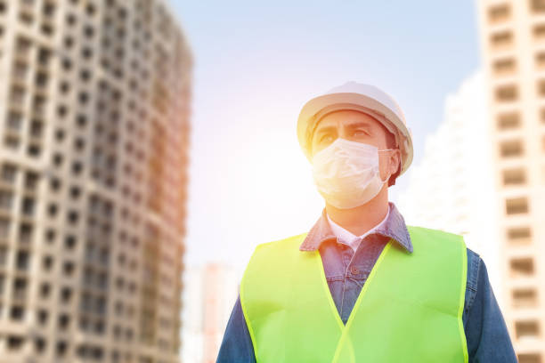 istock Engineer in protective helmet and medical mask  at construction site 1290076223