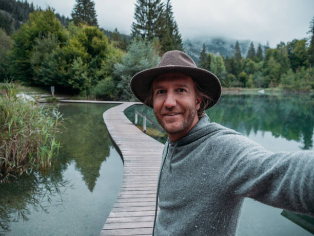 homem tira selfie em doca acima do lago usando celular - telephone nature mobile phone autumn - fotografias e filmes do acervo