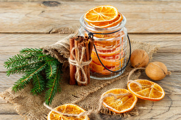 istock Christmas composition with spruce tree branches, cinnamon sticks and garland made of dried slices of oranges on wooden background. Rustic style. 1290077705