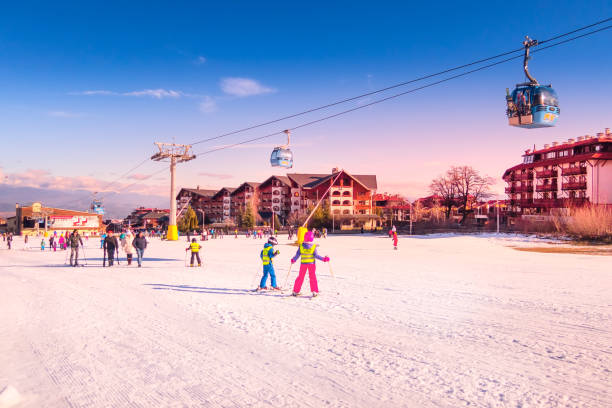Bansko, Bulgaria - January 22, 2018: Winter ski resort Bansko in the morning with ski slope, cable car cabins, people and mountains view
