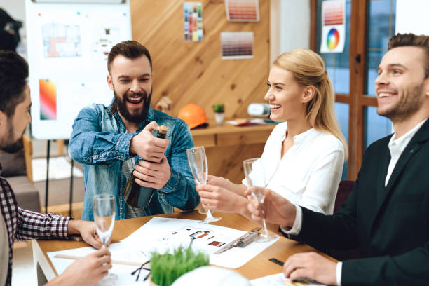 istock Team of designers architects opening champagne. 1290080792