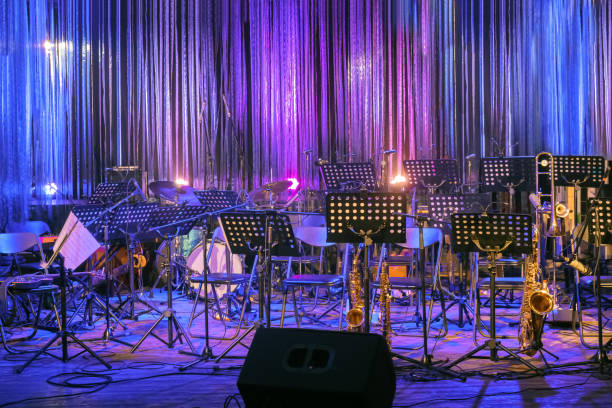 istock Musical Instruments and Sheet Music Standing Ready on a Stage for a Live Performace at Rock or Jazz Concert or Festival in Colourful Lighting. Empty Stage for Orchestra. Online Music Concert or Event 1290082967