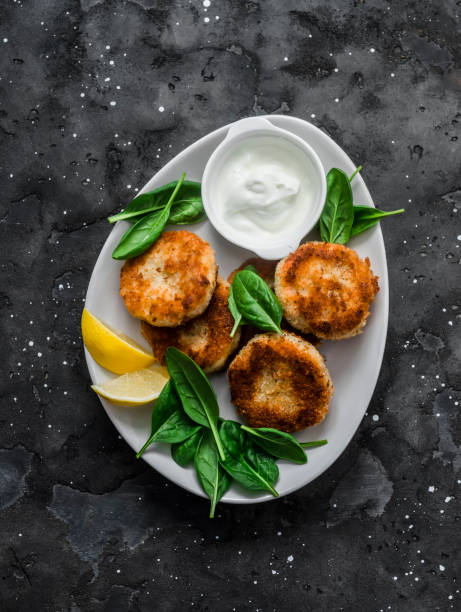 thunfisch- und kartoffelschnitzel mit spinat und griechischem joghurt auf dunklem hintergrund, ansicht von oben - fish cutlet stock-fotos und bilder