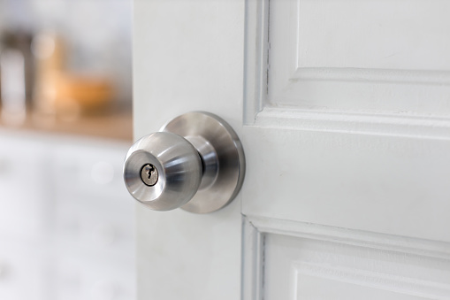 Door with grill, stainless door knob or handle on wooden door in beautiful lighting.a handle on a door that is turned to release the latch.