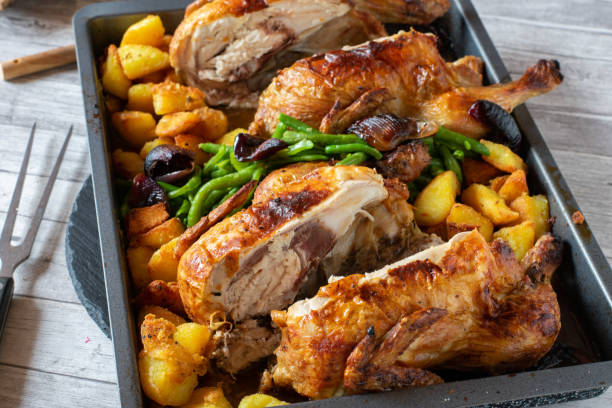 halved chicken with vegetables and potatoes homemade cooked roast chicken dinner with halved chicken, vegetables and roasted potatoes. Topped with caramelized red onions. Ready to eat baking sheet stock pictures, royalty-free photos & images