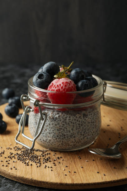 istock Board with jar of delicious chia pudding on black smokey table 1290090054