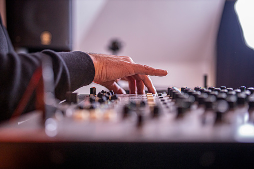 Photo of DJ playing music on sound mixer-hands only.