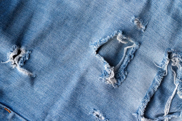 texture bleue de tissu de jeans déchirés. denim affligé avec le fond de trou et de couture - textile canvas torn textured photos et images de collection