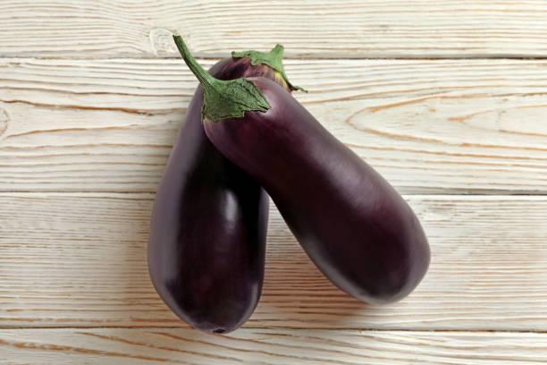 istock Fresh raw eggplants on white wooden background 1290093085
