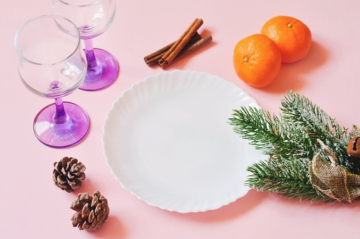 Preparing for Christmas. New Year's table decoration. Two glasses, a platter, tangerines, cinnamon and pine cones. Free space for text