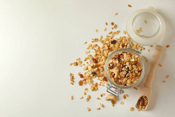istock Glass jar and scoop with granola on white background 1290095646