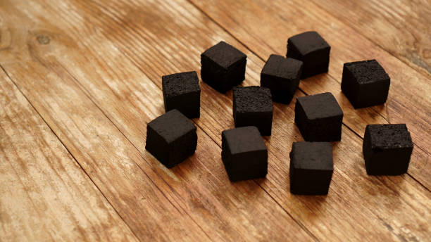 Cubes of coconut coal for hookah on wooden background.