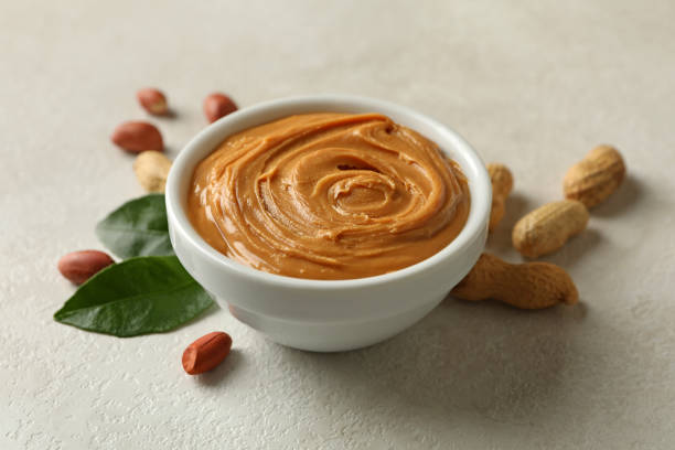 istock Peanut and leaves, and bowl with peanut butter on white background 1290098274