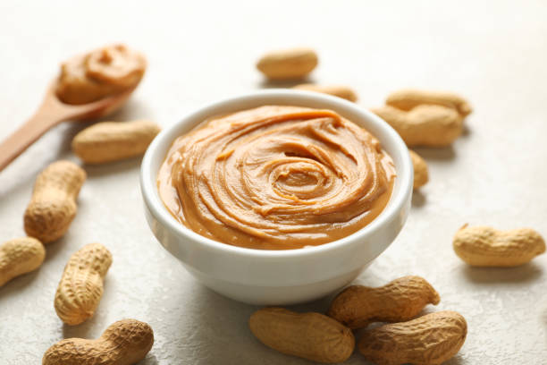 istock Spoon and bowl with peanut butter, and peanut on white background 1290098299