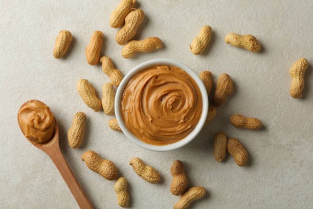 istock Bowl and spoon with peanut butter, and peanut on gray background 1290098867