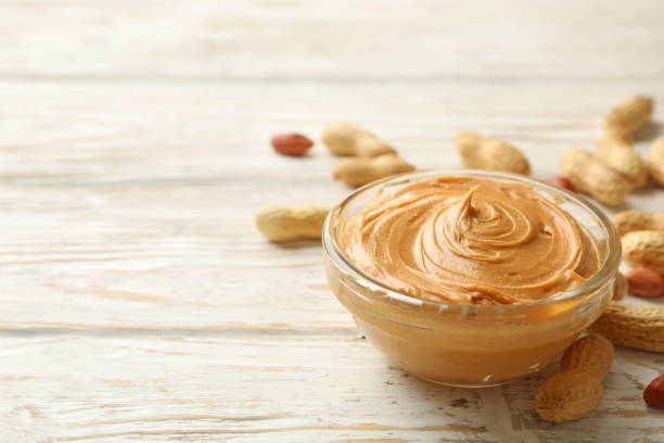 istock Peanut and bowl with peanut butter on wooden background 1290099121