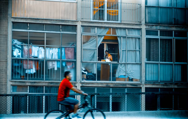 Sao Paulo, Brazil, April 28, 2018 - Giant Worm viaduct  (aka joão goulart viaduct) is a car high transit route, during the week.\nAt weekend, a cyclist strolls over the viaduct, in front of an apartment facade with clothes on the clothesline.