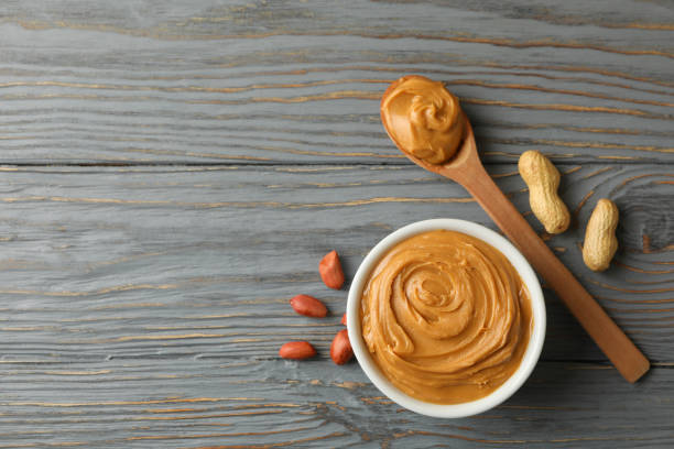 istock Bowl and spoon with peanut butter on wooden background 1290099237