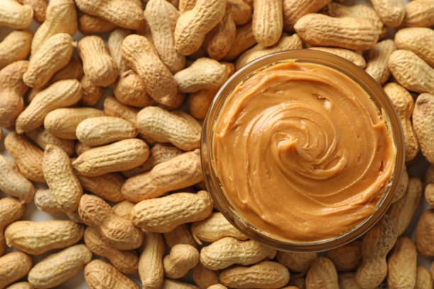 istock Jar with peanut butter on peanut background, close up 1290099312