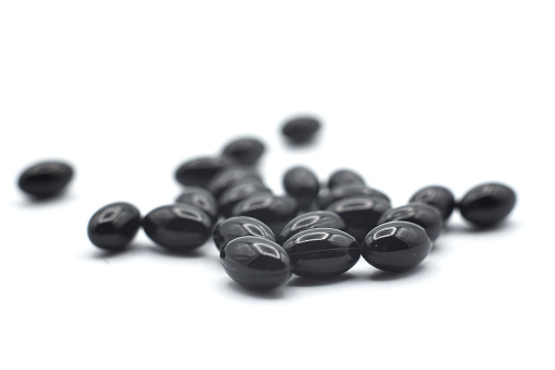 Closeup of black pills of coal on white background