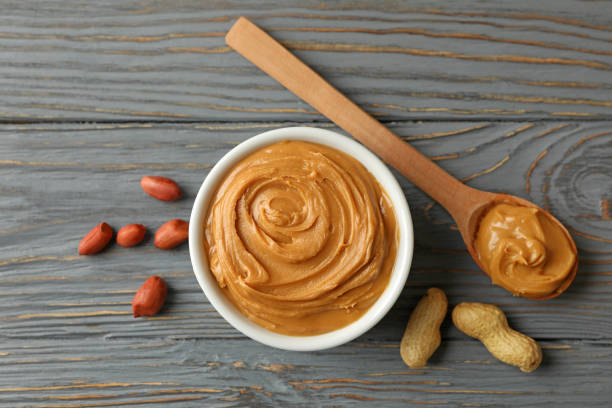 istock Bowl and spoon with peanut butter on wooden background 1290099603